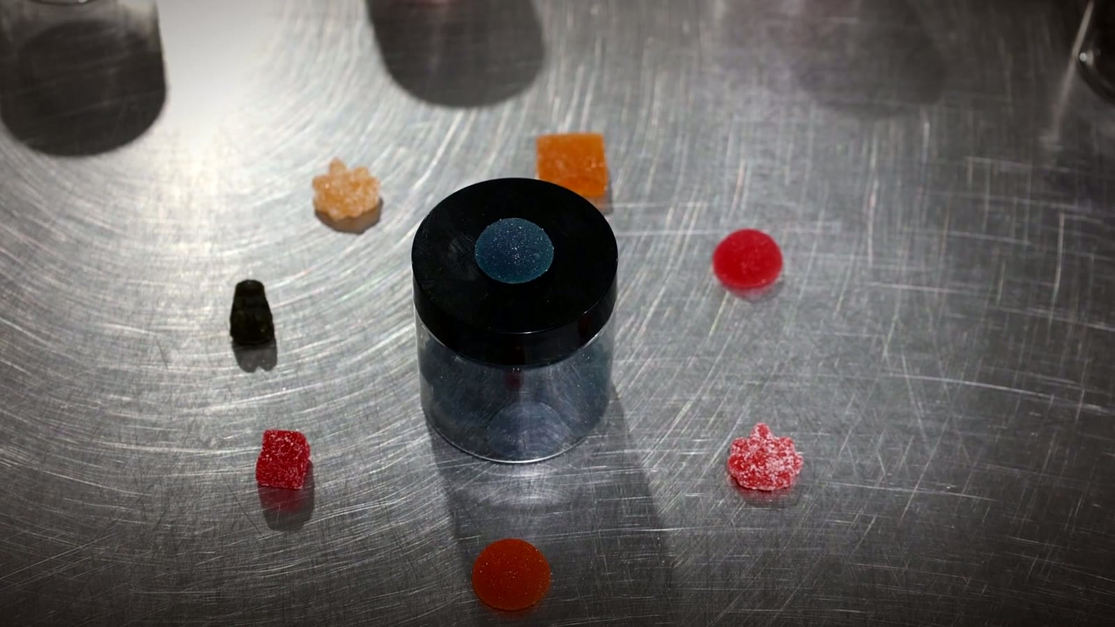 Assorted custom gummy shapes on a stainless steel bench