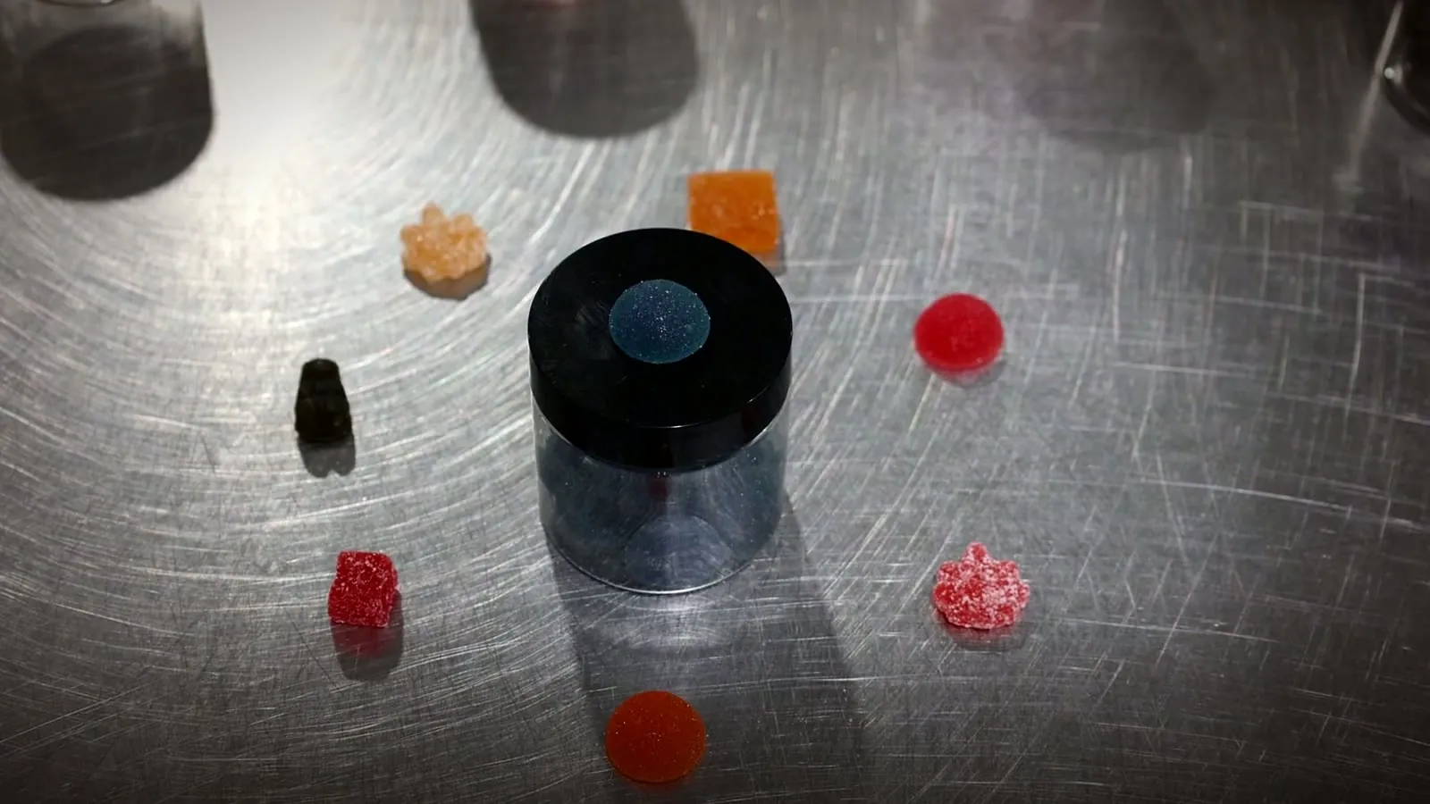 Assorted custom gummy shapes on a stainless steel bench